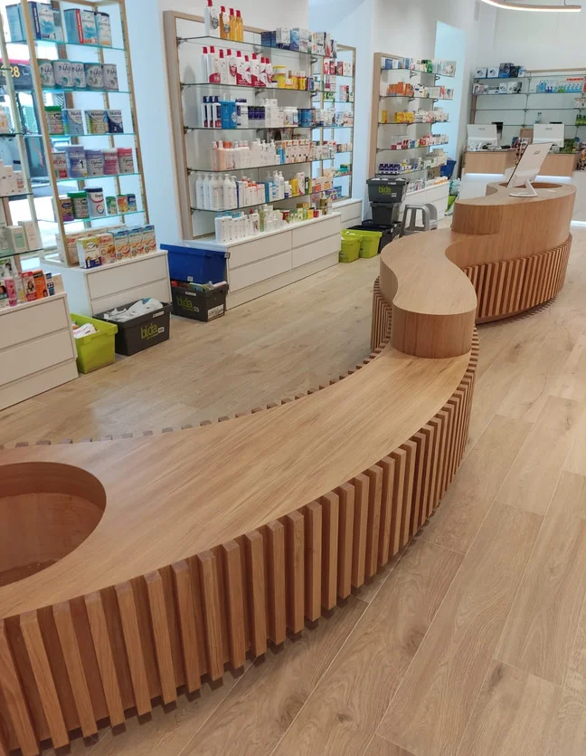 Mostrador curvo en madera. Frente de listones de madera y superficie de atención adaptados a una geometría curva.
